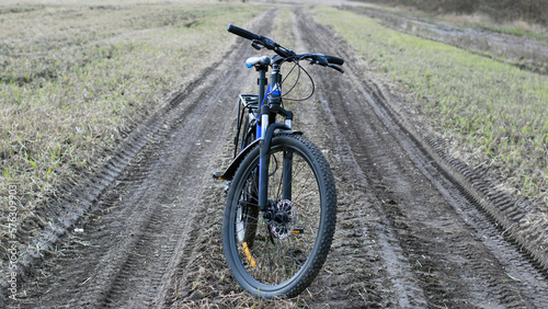 Mountain bike. stands on a field road. spring or autumn. concept of cycling  repair or breakage  sports  outdoor activities. bike on trail  front wheel in focus. healthy lifestyle