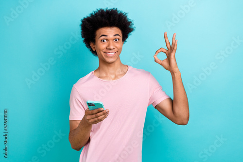 Photo of youngster cheerful optimistic apple smartphone gadget show okey sign fast speed wifi connection internet isolated on cyan color background