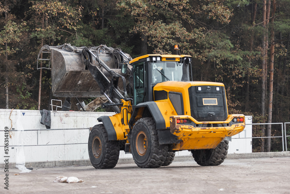 Skid steer loader loading a truck with waste material transferred for further sorting, treatment, and recycling, aerial view. Waste management
