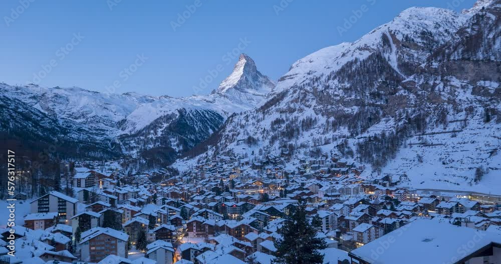 4K Time lapse of Zermatt city Valley famous travel ski resort and iconic Matterhorn peak at dawn in Swiss alps, Switzerland. The snow covered village and church in Canton Valais in winter Timelapse.