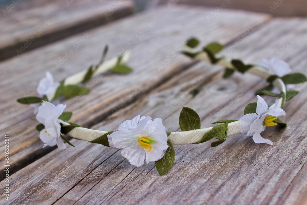 Summer still life photo with a hair band with white flowers lying on light wood.