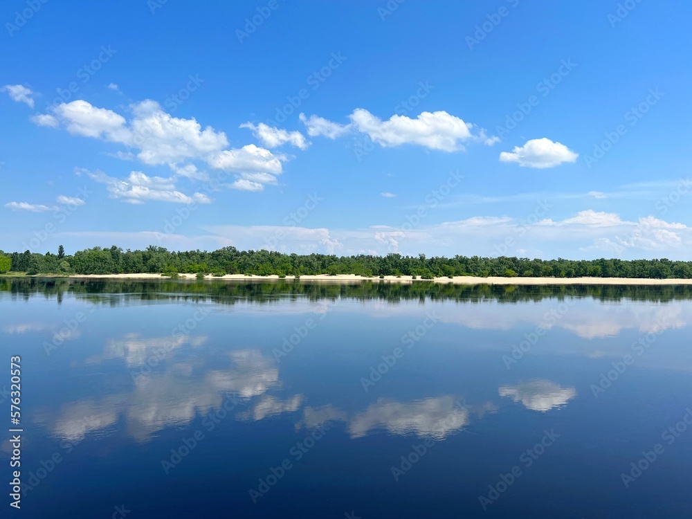 Summer landscape with blue river, sky and sandy beach.