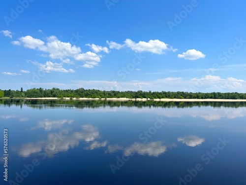 Summer landscape with blue river, sky and sandy beach.