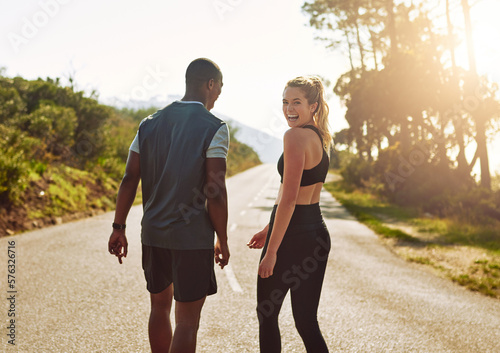 Fototapeta Naklejka Na Ścianę i Meble -  My guy makes the best workout buddy. Shot of a fit young couple slowing down for a walk during their run outdoors.