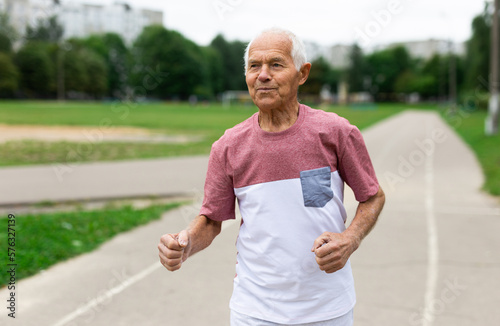 Senior man running through city park