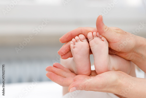 Close up of baby's foots in mother hands. Childhood and baby care concept