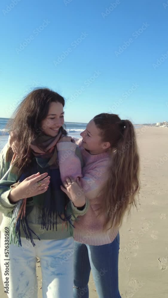Couple of beautiful teenage girlfriends hugging on the beach looking at camera and looking at each other Couple of beautiful teenage girlfriends hugging on the beach looking at camera and looking at each other