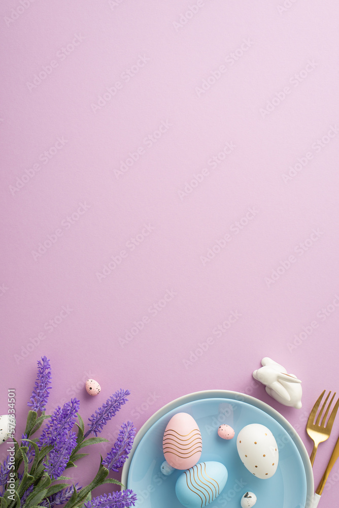 Easter decor concept. Top view vertical photo of blue plate cutlery pink blue white easter eggs ceramic bunny and bouquet of lavender flowers on isolated lilac background with empty space