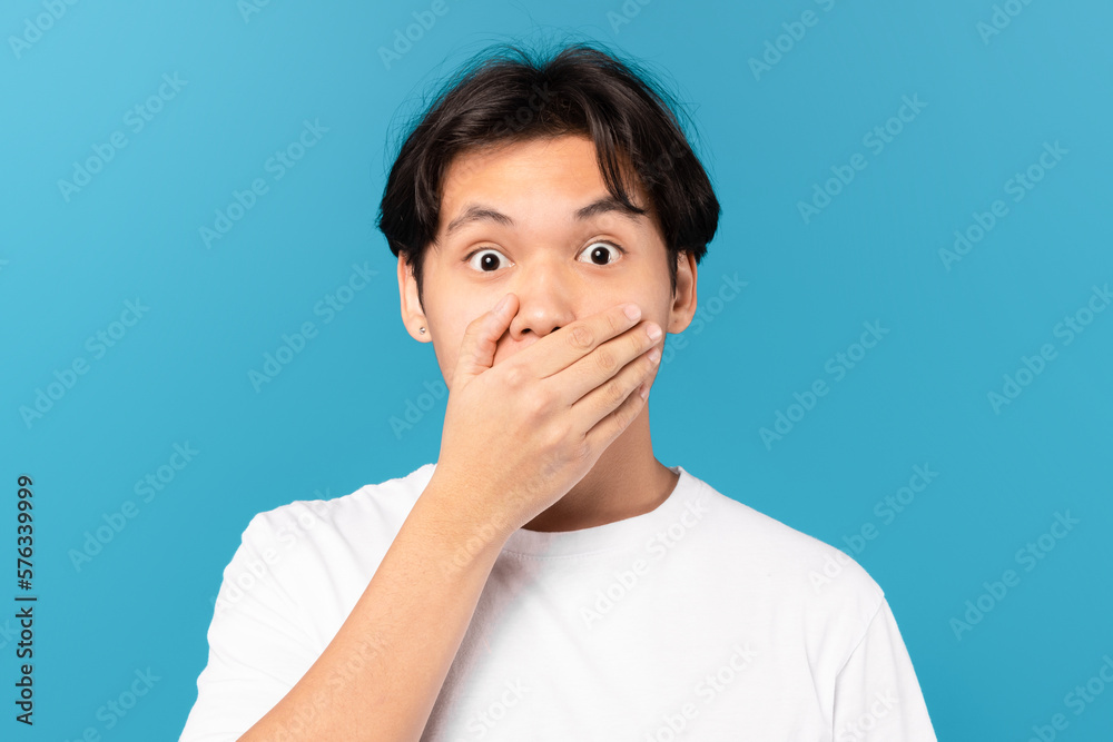 Shocked Chinese Guy Covering Mouth With Hand On Blue Background Shocked Chinese Guy Covering Mouth With Hand On Blue Background