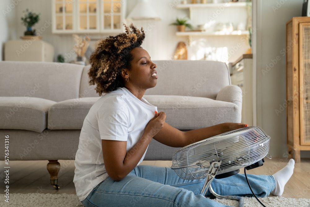 Millennial African American girl sitting on floor in living room