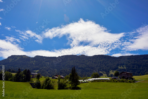 Near the mountain is a large estate with houses and greenhouses against the background of a bright sky