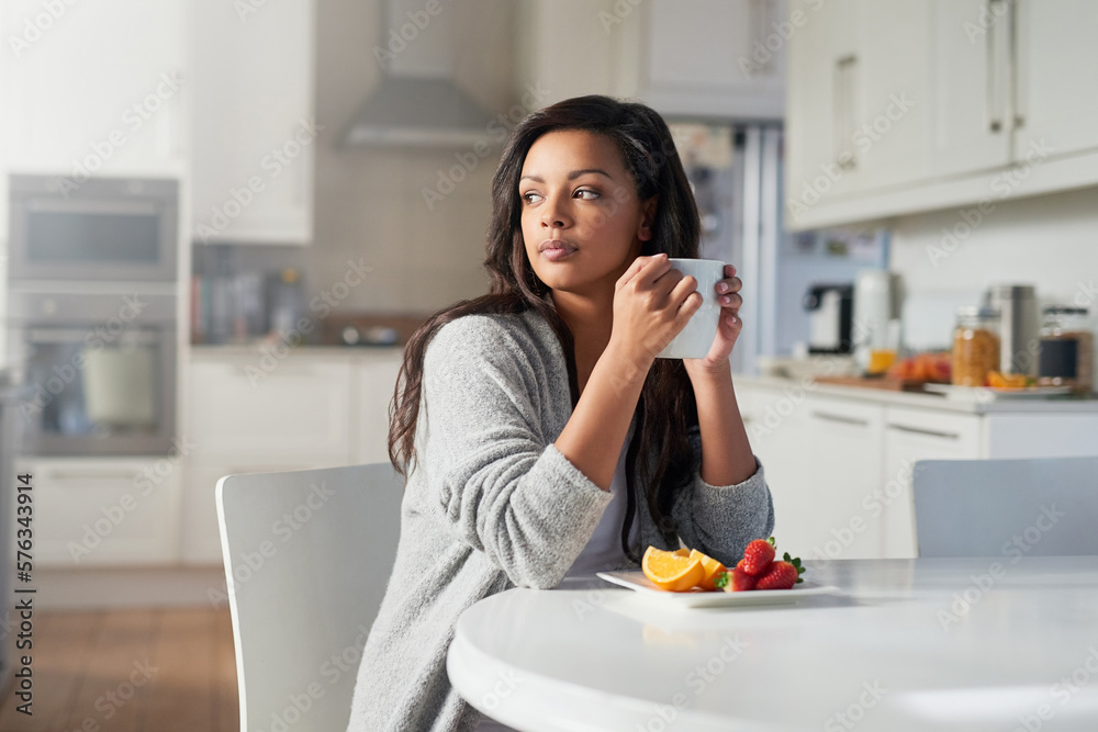 Contemplating the day that lies ahead. Shot of young woman daydreaming while enjoying breakfast in her kitchen at home. Contemplating the day that lies ahead. Shot of young woman daydreaming while enjoying breakfast in her kitchen at home.