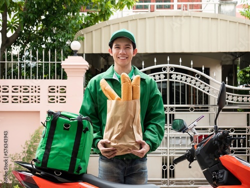 Asian rider man waiting to deliver bakery food in brown paper bag with fast express and kind service