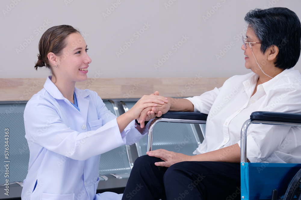 Female doctor with old female patient sitting in a wheelchair