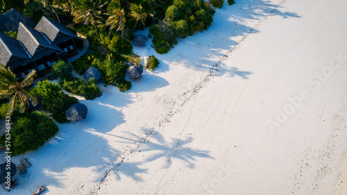 The aerial view of Zanzibar's Indian Ocean coastline is simply stunning, featuring palm trees, white sand, and sparkling blue waters. With luxurious hotels and a tropical landscape, it is the perfect 