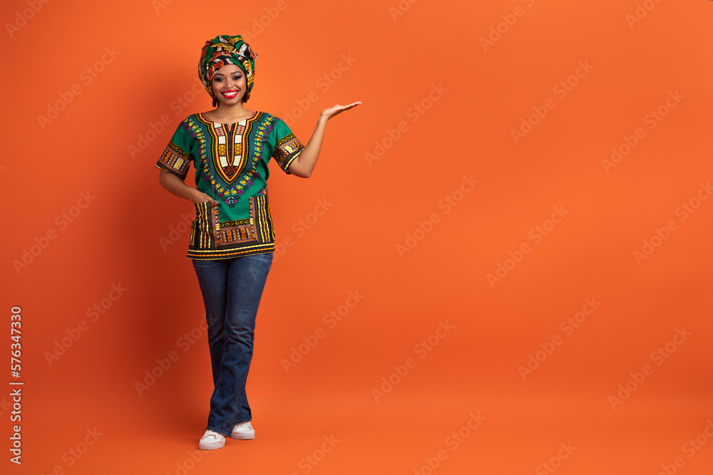 Attractive black lady in colorful outwear pointing at copy space