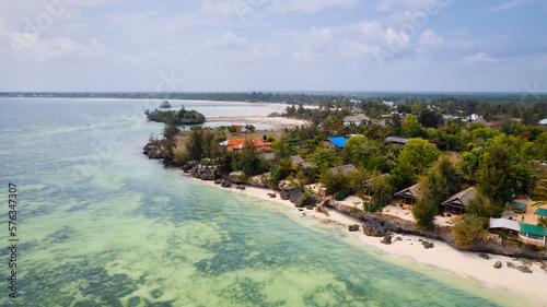 Fototapeta Naklejka Na Ścianę i Meble -  The aerial view of Zanzibar's Indian Ocean coastline is simply stunning, featuring palm trees, white sand, and sparkling blue waters. With luxurious hotels and a tropical landscape, it is the perfect 