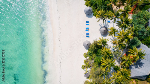 From above, the stunning beauty of Zanzibar's Nungwi Beach is captured in an aerial view with a yacht and palm trees on the sandy beach.