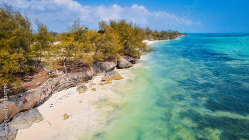 The aerial view of Zanzibar's Indian Ocean coastline is simply stunning, featuring palm trees, white sand, and sparkling blue waters. With luxurious hotels and a tropical landscape, it is the perfect 