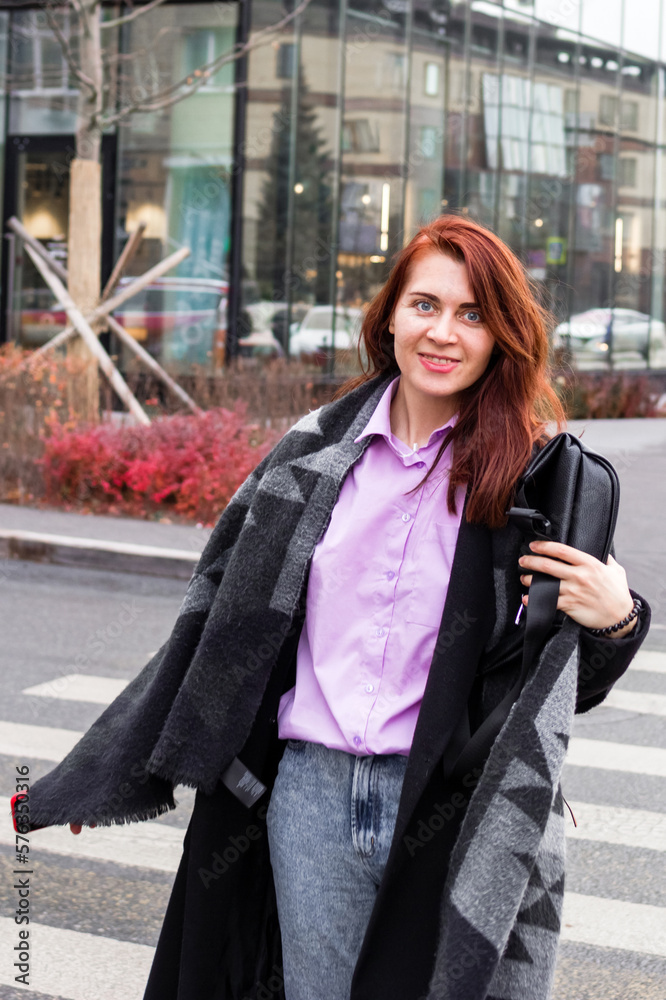 Fototapeta premium Lifestyle portrait of beautiful smiling business woman in casual clothing is walking in a city.