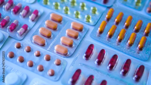 Many colored tablets in pharmaceutical blisters lying on desk, large selection of antimicrobial, antihistamines and antiviral drugs, preparation for the cold season