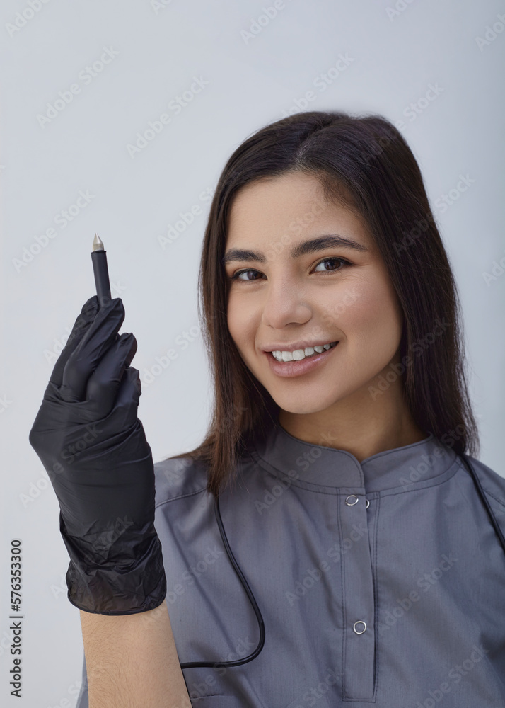 a happy woman, a master of electroepilation holds a tool in her hands and smiles happily a happy woman, a master of electroepilation holds a tool in her hands and smiles happily