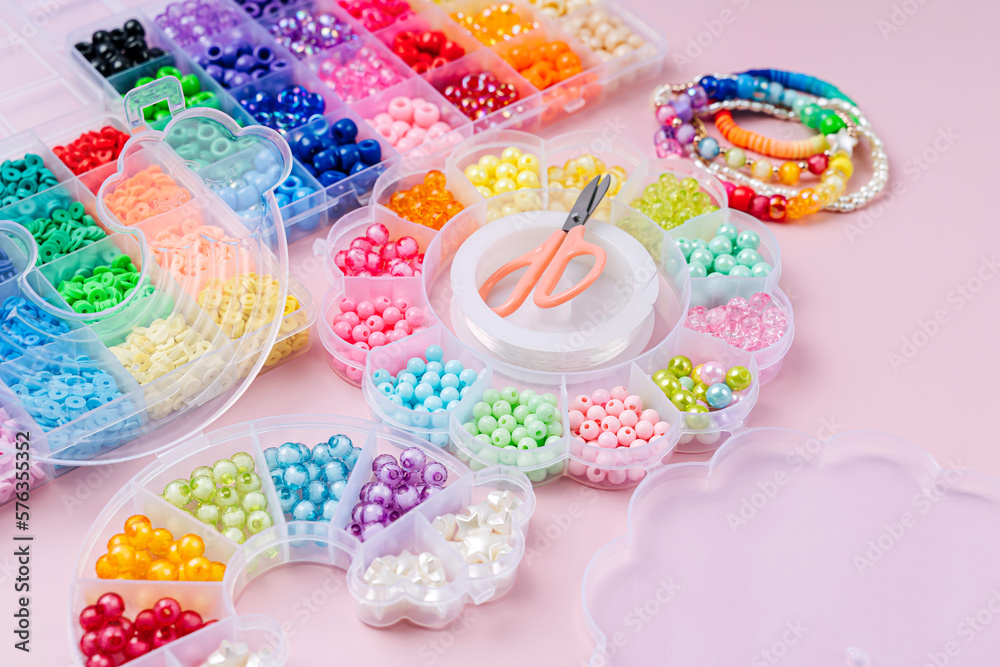 Kids handmade beaded jewelry and different multi-colored beads for children's needlework and crafts in boxes. DIY art activity for kids. Motor skills, creativity and hobby. Kids handmade beaded jewelry and different multi-colored beads for children's needlework and crafts in boxes. DIY art activity for kids. Motor skills, creativity and hobby.