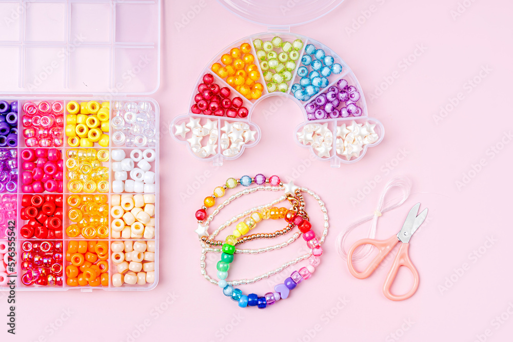 Kids handmade beaded jewelry and different multi-colored beads for children's needlework and crafts in boxes. DIY art activity for kids. Motor skills, creativity and  hobby.