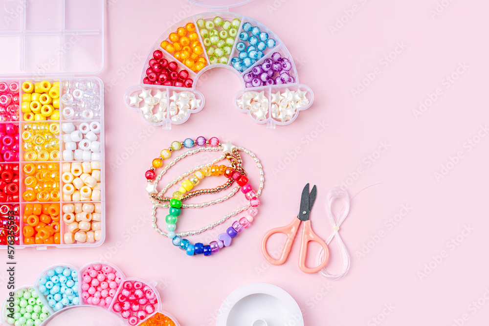 Kids handmade beaded jewelry and different multi-colored beads for children's needlework and crafts in boxes. DIY art activity for kids. Motor skills, creativity and  hobby.