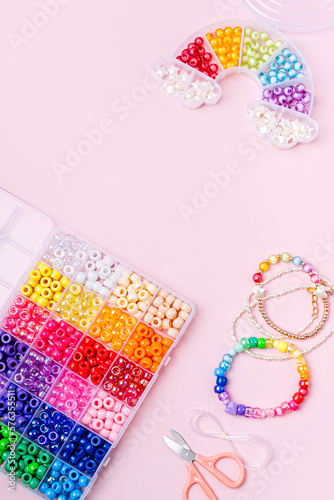 Kids handmade beaded jewelry and different multi-colored beads for children's needlework and crafts in boxes. DIY art activity for kids. Motor skills, creativity and hobby.