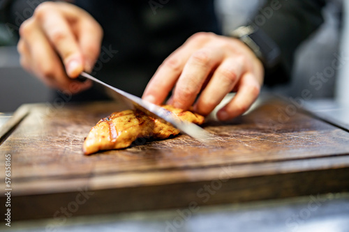 chef is cutting the chicken fillet in a restaurant kitchen