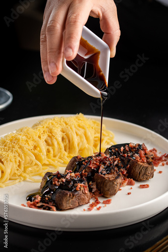 salsa callendo en una carne con tocineta y espagueti photo