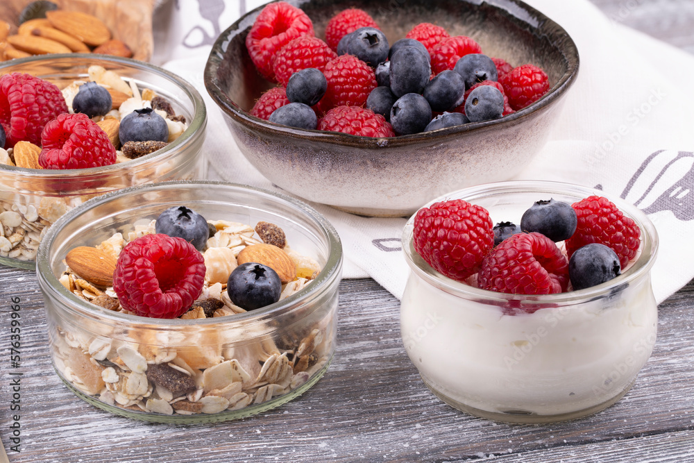 Close-up of granola with nuts, raspberries and blueberries, yogurt on a gray whitewashed rustic table, copy space. healthy breakfast Close-up of granola with nuts, raspberries and blueberries, yogurt on a gray whitewashed rustic table, copy space. healthy breakfast