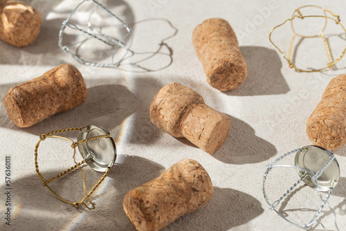 Creative composition made of champagne corks on beige sunlit background with shadow. Bottle caps from sparkling wine and metal wire muselet. Summer party drink concept