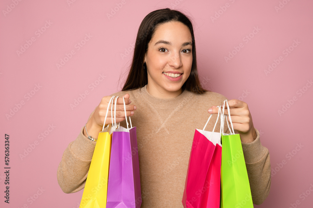 Shopping woman happy smiling holding shopping bags isolated on pink background. Lovely fresh young Caucasian female model.