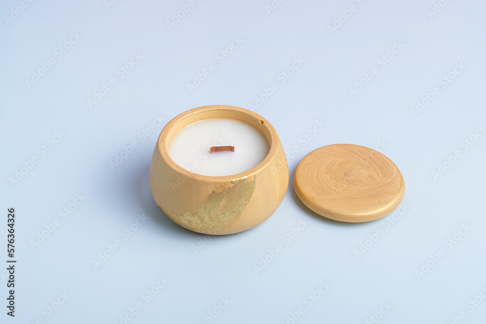 Interior candle in a plaster candlestick with lid. Handmade candle on blue background Interior candle in a plaster candlestick with lid. Handmade candle on blue background