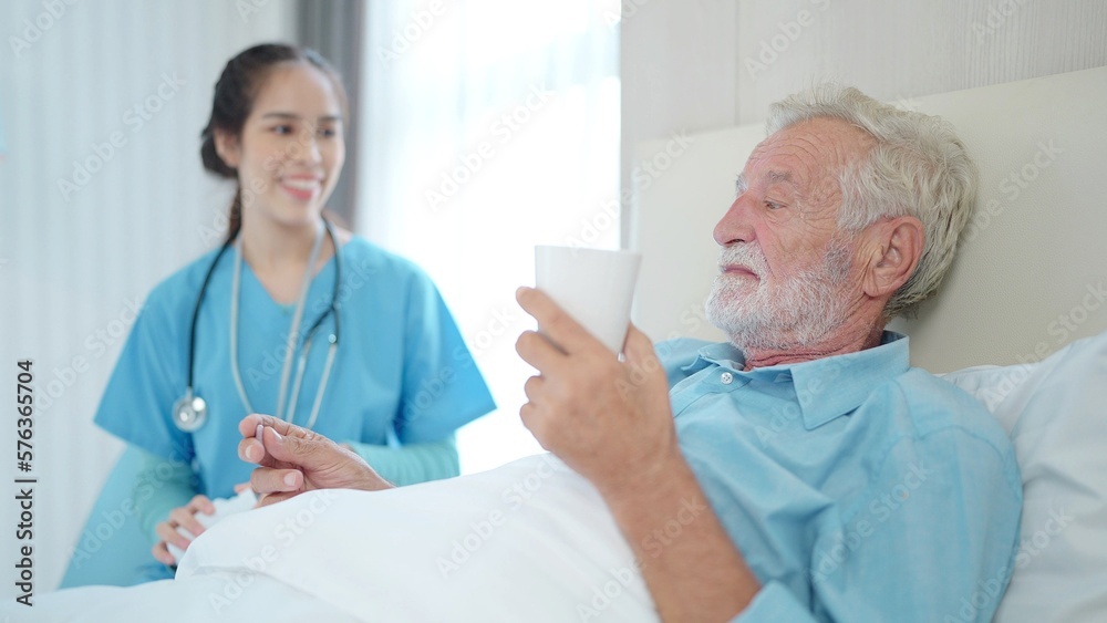 Nurse giving medication and glass of water to senior man on the bed at hospital ward, Medicine health care and elderly people concept Nurse giving medication and glass of water to senior man on the bed at hospital ward, Medicine health care and elderly people concept