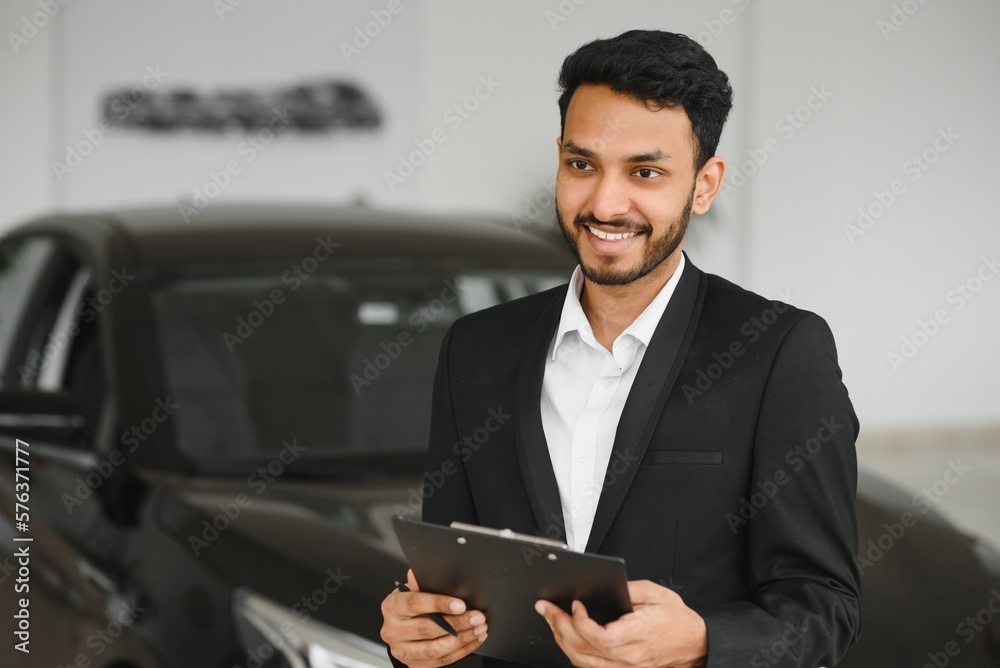 indian cheerful car salesman showing new car at showroom