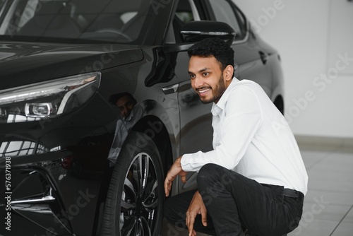 happy indian man buy new biodiesel eco automobile in lux showroom. © Serhii