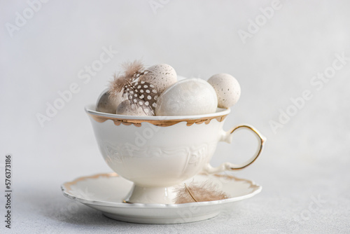 Close-up of assorted eggs and quail feathers in a vintage tea cup