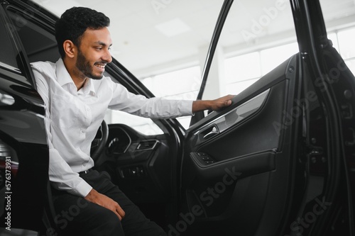 Young man sitting inside new car. Smiling