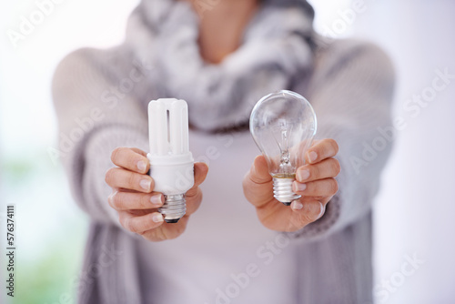Keep the lights burning longer. A cropped image of a woman holding two different lightbulbs. photo