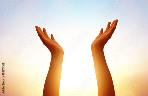hands praying on blurred sunset sky background