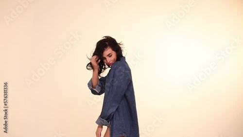 Young sexy girl in a blue denim shirt and black lingerie with curly black hair posing on a white background. Young woman in an unbuttoned denim shirt and black sexy lingerie on a white background. photo