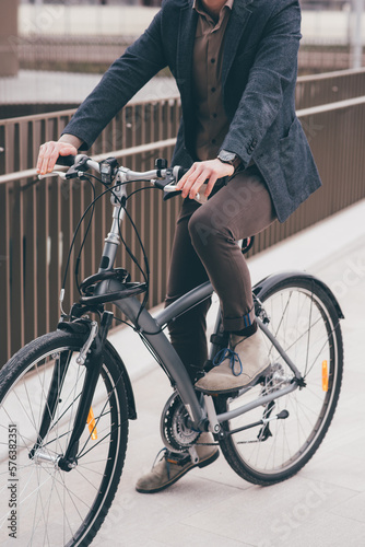 Unrecognizable contemporary stylish businessman going to work by bike