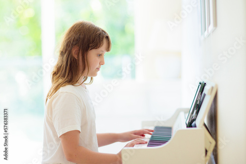 Child playing piano. Kids play music. © famveldman