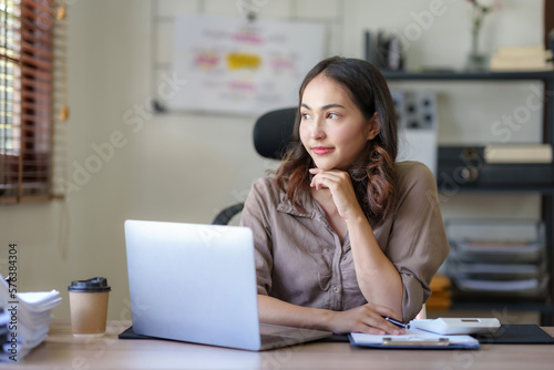 Attractive asian businesswoman sitting working on laptop thinking new idea at office.