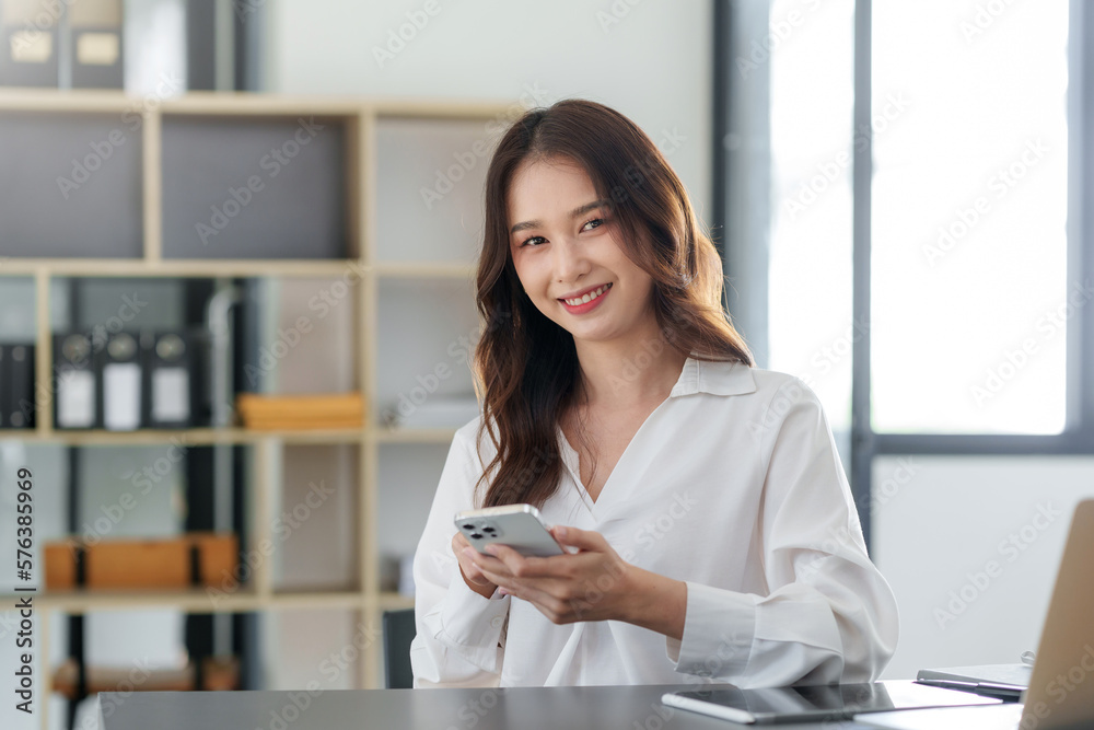 Smiling Asian businesswoman using smartphone at office. Smiling Asian businesswoman using smartphone at office.