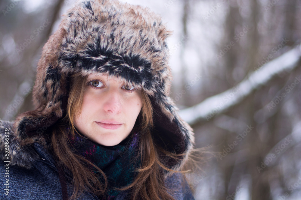 Young caucasian woman in winter hat and coat. Headshot photo in snowy forest in winter.
Young caucasian woman in winter hat and coat. Headshot photo in snowy forest in winter.