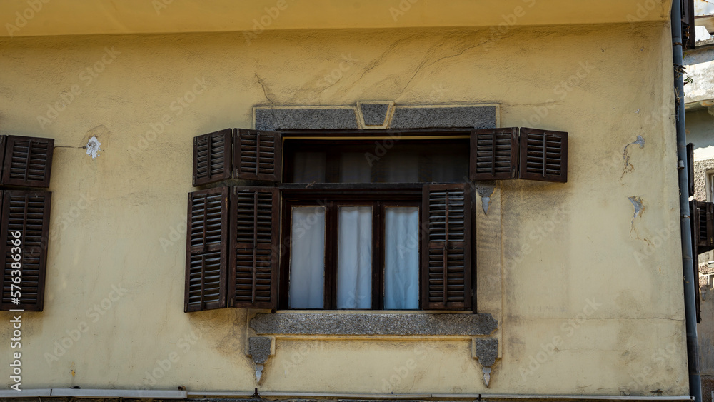 Old wooden window with wooden shutters and stone frame on an old cracked yellow wall in Antakya before the earthquake of 2023. 